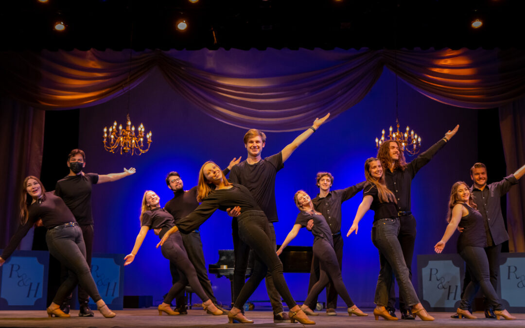 A photo of the cast of "It's a Grand Night for Singing" center stage, striking a pose.
