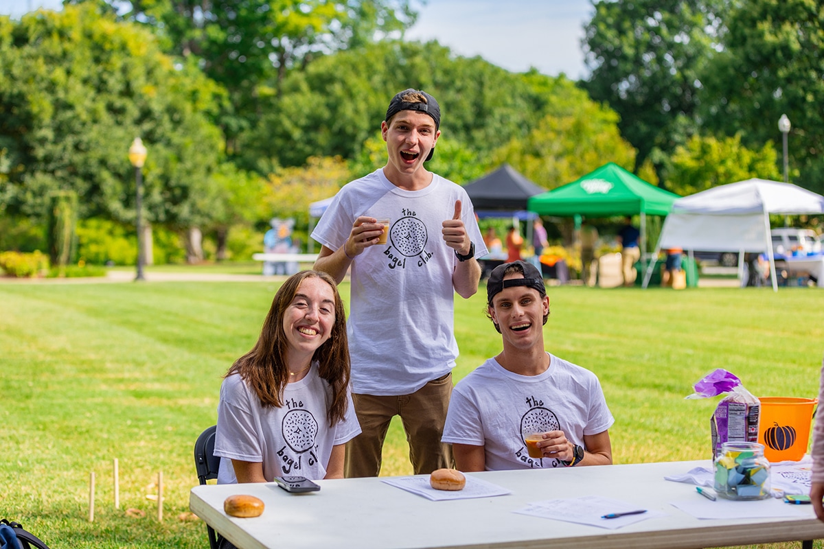 students in bagel club handing out bagels on a sunny day