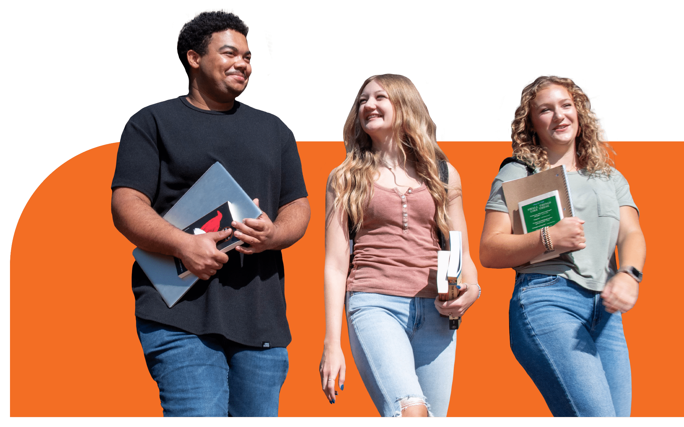 students walk to class holding books and laptops