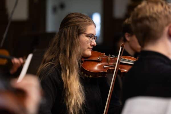 female student in violin at orchestra music concert