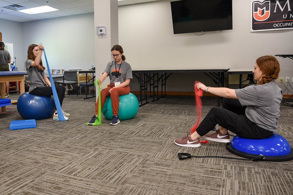 MiLLigan Collage kids learn how to stretch with bands during occupational therapy camp